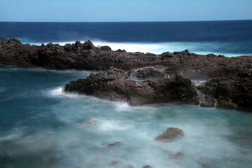 Fototapeta na wymiar Detail of rocks with waterfalls of ocean water.