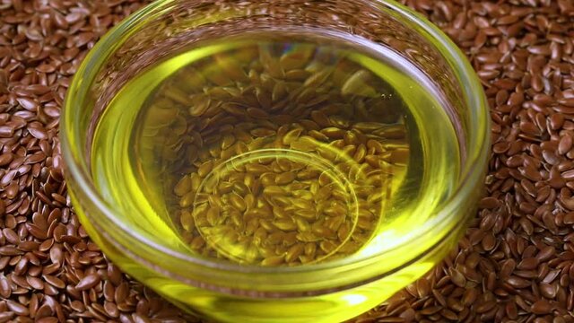 Brown Linseeds full frame and a glass bowl with linseed oil in the middle close up