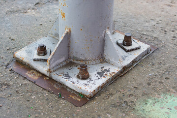 fastening with bolts and nuts of an old and rusty supporting beam to a concrete base