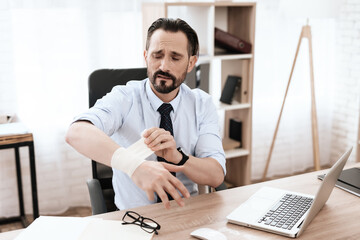 A man sits at work and rewinds an injured hand. 