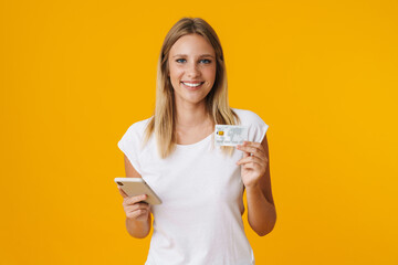 Cheerful blonde girl using mobile phone and credit card