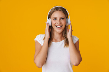 Cheerful blonde girl smiling while listening music with headphones