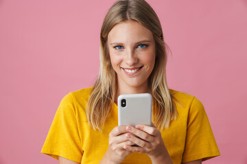 Cheerful blonde girl smiling and using mobile phone