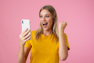 Excited girl making winner gesture while taking selfie on cellphone
