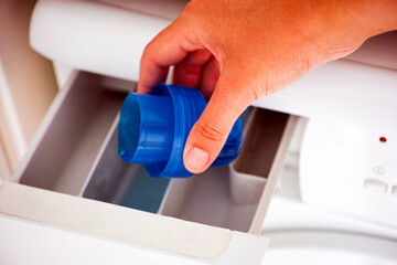 woman hand pouring liquid detergent in the washing machine