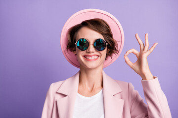 Photo of toothy beaming girl woman wear pink vintage outfit cap glasses showing okey one hand isolated purple color background