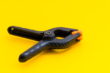 close-up photo of a clamp isolated on a yellow background