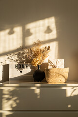 Home interior. A vase of dried flowers on a chest of drawers. Cozy home