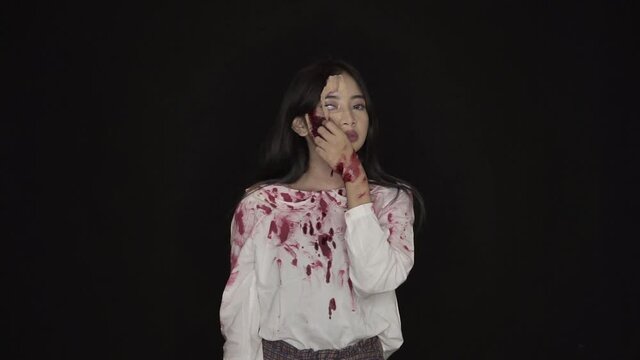 The beautiful young woman is peeling her face until it looks ugly. With half of his face covered in blood wounds, and clothes covered in fresh blood.