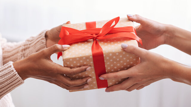 Female hands holding and giving present to woman