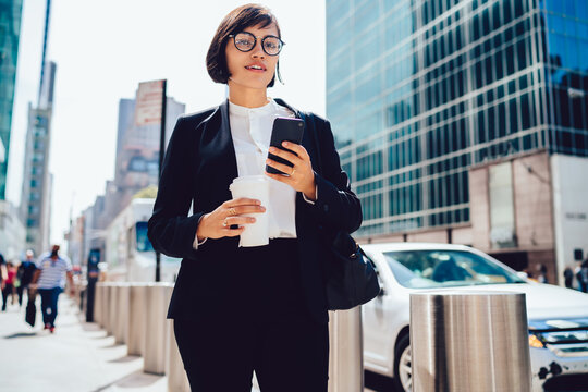 Formal businesswoman with takeaway coffee using smartphone