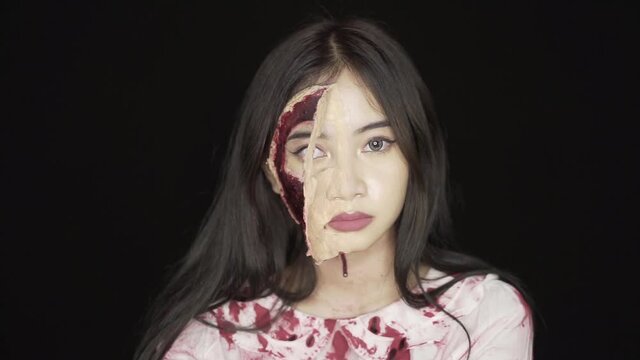 An ugly woman full of revenge prepared to kill someone with her hand. With half of his face covered in blood wounds, and clothes covered in fresh blood.