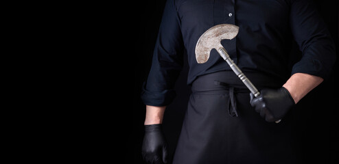 Fototapeta na wymiar man in black clothes, latex gloves holds a vintage metal ax-knife for meat and vegetables