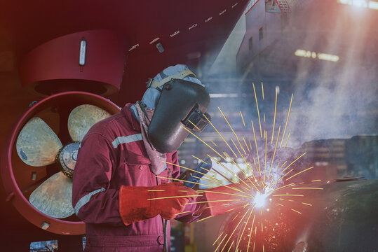 Industrial welding process with equipment protective mask welder, leather gloves, PPE at construction site, business concept with technician focus on propeller Repair background.
