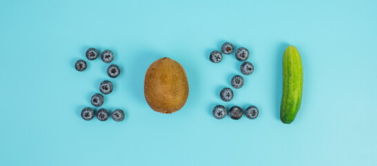 2021 Happy New Year and New You with fruits and Vegetables; Blueberries, Kiwi and cucumber on blue background. Goals, Healthy, Resolution, Time to New Start and dieting concept