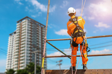 Safety sprinkling worker on high with scaffolding  wear dresses and safety man with harness safety concept on steel structures success from work in site construction building on blue sky background.