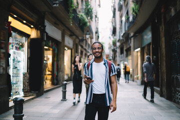 Cheerful man with smartphone on pedestrian street