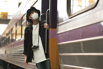 Asian travelers men and camera in train station with medical face mask to protection the Covid-19, new normal lifestyle