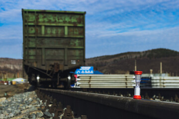 Obraz premium Railway freight cars on rails with hourglass, the concept of saving time on railway transportation.