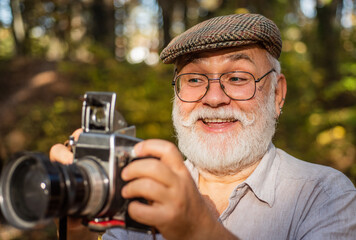 wow i like it. Capture memories from trip. portrait of man holding vintage camera. mature man in glasses. selective focus. Confident photographer. Closeup portrait of man holding vintage photo camera