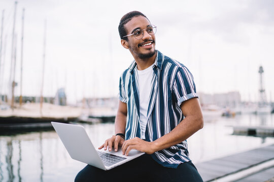 Happy ethnic man in glasses working on project