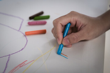 The child is painting with crayons on white paper.