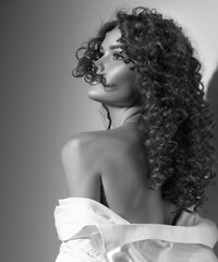 Beautiful young woman with curly hair posing, beauty model portrait, closeup. Beautiful sexy model girl in white cotton shirt. Flying hair, perfect make-up. Hairstyle. Black and white image