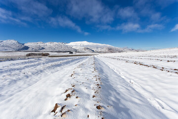 Wide agle view of a ploughed farmland on a hill covered in thick snow with matroosberg Mountain on the horizon close to Ceres in the Western Cape of South Africa