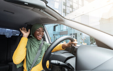 Road Fun. Joyful African Muslim Woman In Hijab Dancing In Car