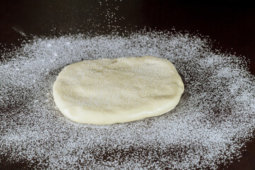 White fondant on dark kitchen table. Making cake decoration.