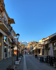Typical street of Chania, Crete, Greece with shops, cafes and restaurants for evening promenade. No tourists, early morning. Snow on Cretan mountains
