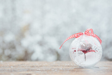 Beautiful Christmas bauble decorations lie on the wooden table over snow covered forest background.