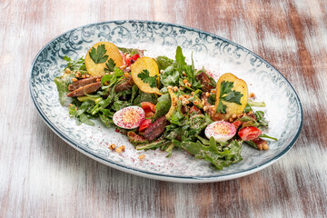 Duck breast salad with potato chips and fresh vegetables. On a decorative plate