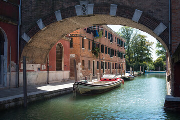 scorcio di un canale minore di Venezia, con un edificio industriale di mattoni rossi, ex...