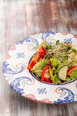 Homemade salad with fresh vegetables and microgreen on a decorative plate