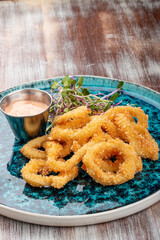 Squid rings fried in batter with sauce on a decorative plate