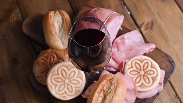 A glass of red wine, mortadela, Tigelle and different breads on a wooden table. A traditional pre-dinner starter in the northern Italian region of Emilia Romagna. footage