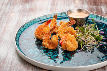 Fried tiger prawns with sauce on a decorative plate