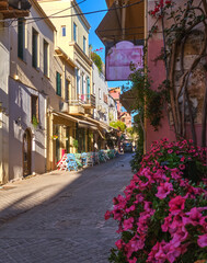 Fototapeta na wymiar Beautiful view of narrow streets of old town of Chania, Crete, Greece in early morning. Street cafes and restaurants. Selective focus. Pink petunia.