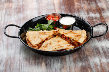Quesadilla with pork, cheese and paprika. In a metal frying pan. Traditional Mexican dish