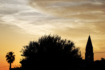 view of an silhouette church tower and palm against a sunset sky