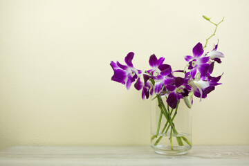 A bouquet of purple orchids in a glass jar is placed on the desk