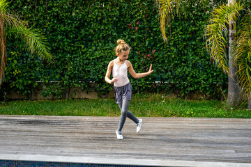 Girl in ballerina's costume dancing in the park. Attractive dancer performer workout at the autumn garden. Active and healthy kid have fun outdoor.