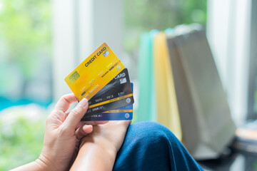 Close up hands holding many credit card with shopping bags. Focus on hand