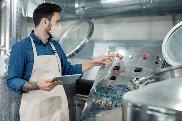 Worker starts production of craft beer at factory at covid-19 pandemic