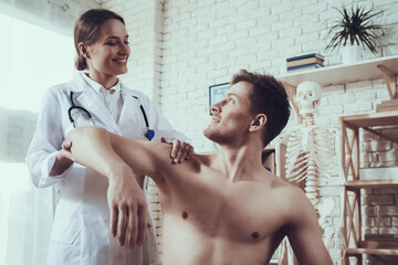 A man with a naked torso looks at a woman doctor.