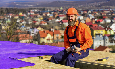 roofer working on roof structure of building on construction site. roofer wear safety uniform...
