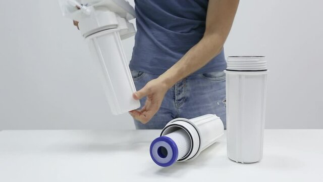 Male hands during process of assembling, screwing cylinders on the reverse osmosis water filterm with partially permeable membrane