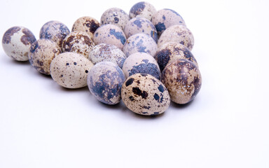 Fototapeta premium Quail eggs laid out in a triangle shape, close-up on a white background, copy space
