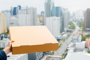 Online delivery service, Virus outbreak  concept. Woman' hand holding pizza boxes, cardboard box and town background. Copy space